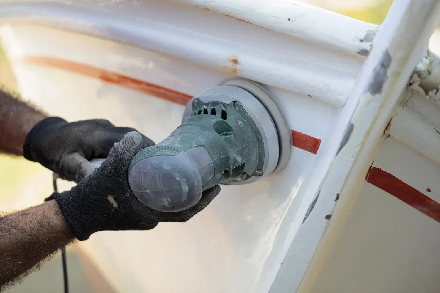 Technician working compound across a boat's exterior surface